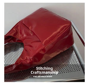 Detailed view of red patent leather tote bag showing high-quality stitching craft