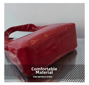 Detail showing high-quality stitching on red glossy patent leather shoulder bag base
