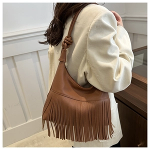Detail of caramel fringe shoulder bag with bohemian tassels and knotted strap design