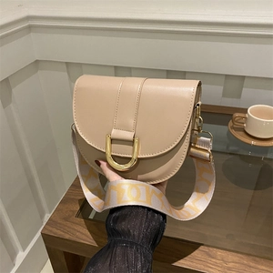 Chic beige saddle bag with gold horseshoe buckle and patterned wide fabric strap