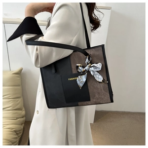 Detail of a two-tone leather tote with 'FASHION' text and a blue polka dot silk scarf