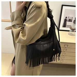 Detalle de bolso de hombro en cuero granulado negro con flecos largos y correa con nudo