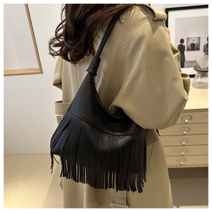 Detail of black pebbled leather tote bag with long hanging fringes and a crescent shape