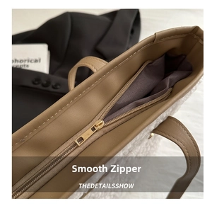 Detail of gold metal zipper and leather trim on plush white fleece tote bag