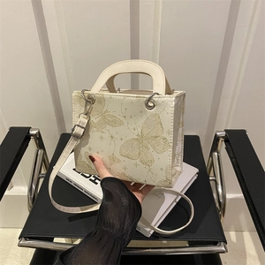 Elegant off-white handbag with golden butterfly print and circular handle for women