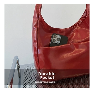 Close-up of bright red patent leather shoulder bag showing durable exterior slip pocket