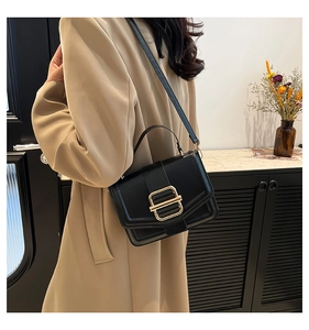Gros plan d'un sac bandoulière en cuir noir avec une boucle métallique dorée élégante