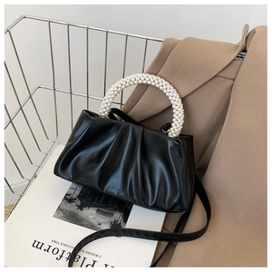 Detail of black cloud bag with pleated leather texture and pearl beaded top handle