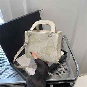 Elegant cream tote bag with gold butterfly embroidery on luxury display box