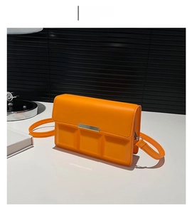 Detail of orange square crossbody bag with chocolate grid pattern and silver metal trim