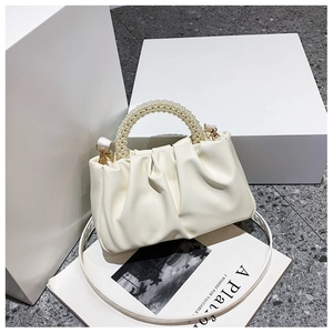 Detail of creamy white cloud bag featuring pearl handle and soft pleated faux leather texture