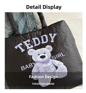 Detailed shot of black quilted tote bag featuring a purple teddy bear graphic and text