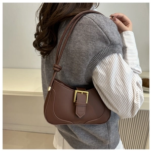Sac demi-lune marron en cuir avec boucle dorée porté par un mannequin en studio