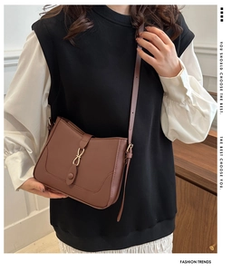 Detailed view of brown faux leather shoulder bag with gold ring buckle and long strap
