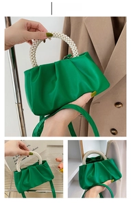 Detail view of green satin cloud bag featuring pleated design and pearl bead handle