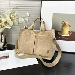 Large beige corduroy tote bag with dual front pockets and adjustable shoulder strap