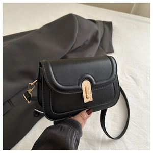 Detailed close-up of a black matte faux leather crossbody bag with a gold metal twist lock