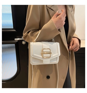 Gros plan sur un sac blanc à boucle dorée porté par un mannequin en blazer kaki