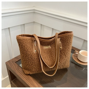 Close-up of brown plush tote bag featuring leather straps and golden rivet accents
