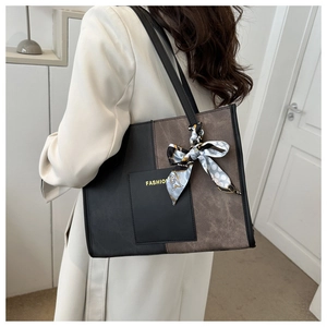 Detail of a large tote bag featuring contrast stitching and a polka dot silk scarf handle