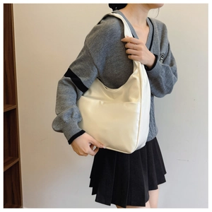 Detail of minimalist cream leather hobo tote bag featuring a large front slip pocket