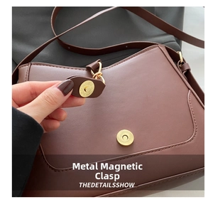 Detailed close-up of the premium gold-tone magnetic clasp on the brown leather bag