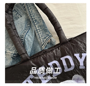 Detail of black quilted nylon bag featuring purple TEDDY print and plush texture