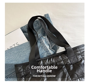 Close-up of black quilted nylon tote bag with reinforced handles and glossy finish