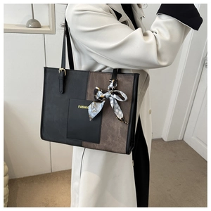Detail of two-tone tote bag featuring FASHION text and elegant floral silk scarf accessory