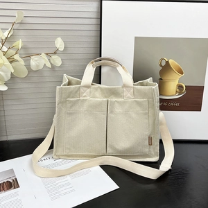 Minimalist beige corduroy tote bag with dual front pockets and woven shoulder strap