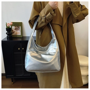 Detail showing the shiny silver liquid metallic texture and soft leather pleats of the hobo bag