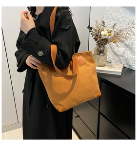 Close-up of yellow corduroy tote bag with vertical texture and reinforced leather corners