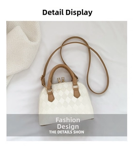 Detail of white quilted shell bag with brown handles and golden zipper hardware