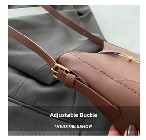 Detail of adjustable gold buckle and fine stitching on dark brown leather handbag
