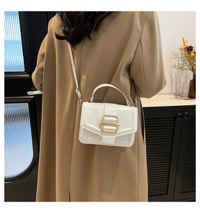 Sac à main blanc en cuir avec boucle dorée porté avec un trench-coat beige élégant