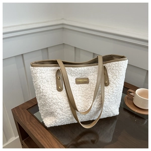 Detail view of white fleece tote bag featuring brown leather trim and a central logo patch