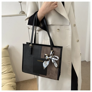Detail of color-block tote bag in black and brown with silk scarf and gold lettering