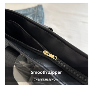 Detail of smooth gold metal zipper and black quilted nylon fabric on a stylish tote bag