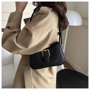 Détail d'un sac à bandoulière en cuir PU noir avec boucle dorée sur un trench beige