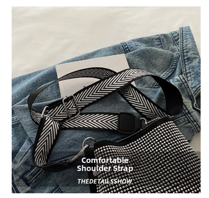 Detail of wide woven strap with chevron pattern and silver buckle on black studded bag