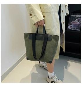 Detail of dark green corduroy tote bag with black handles and reinforced leather corners