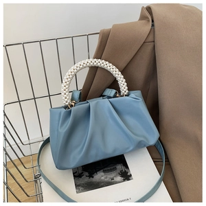Detail of light blue cloud bag with white pearl handle and soft pleated faux leather texture