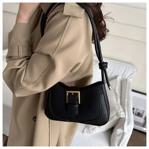 Détail du sac sous le bras en cuir noir avec boucle dorée et bandoulière nouée