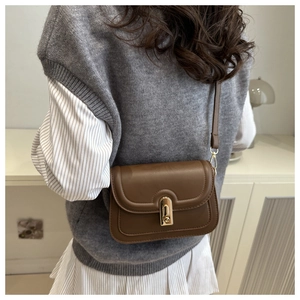 Detailed view of a vintage brown leather crossbody bag with a gold metal lock buckle