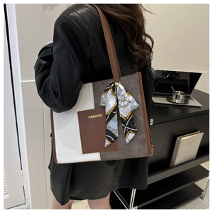 Detail view of large color-block tote bag with silk scarf and gold fashion text