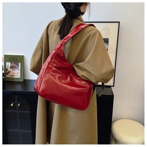 Detailed side view of high-gloss red patent leather large hobo tote bag on shoulder