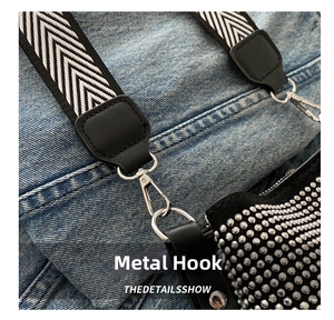 Detail of silver metal spring hook and black white herringbone strap on bucket bag