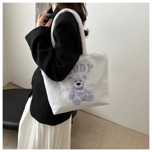 Detail of white quilted puffer tote bag with purple teddy bear print and text