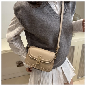 Detail einer minimalistischen beigen Leder-Umhängetasche mit goldener Schließe am Model