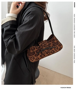 Detail of leopard print baguette bag with black leather straps and velvet texture
